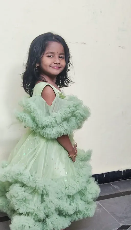 a little girl in a green dress posing for a picture