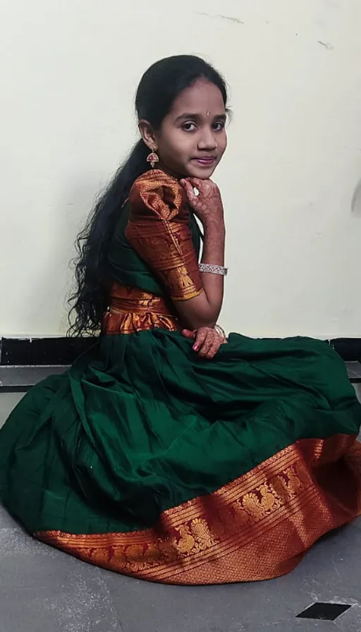 a young girl in a green and gold dress