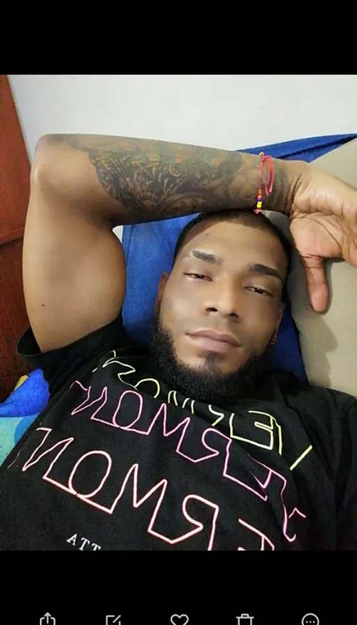 a man laying on a bed with a tattoo on his arm