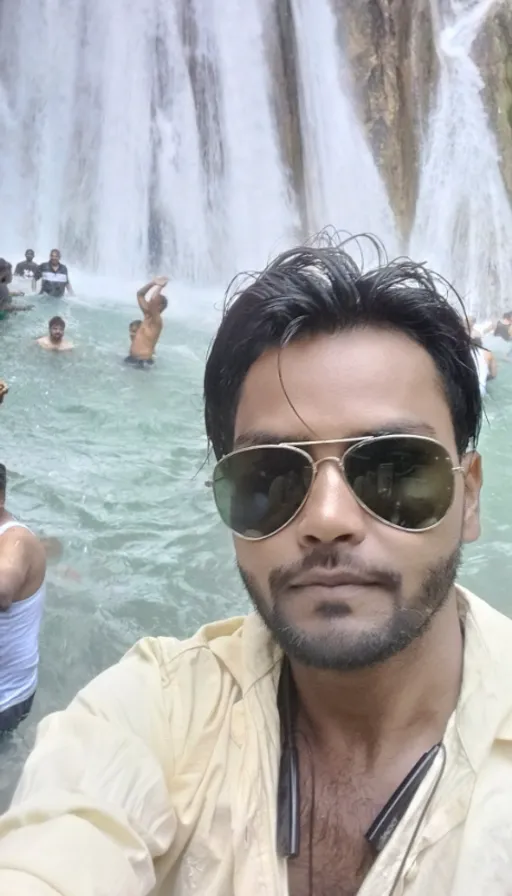 a man taking a selfie in front of a waterfall