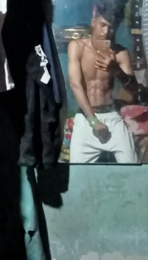 a shirtless man sitting in front of a mirror