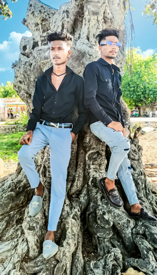 two men sitting on top of a tree trunk