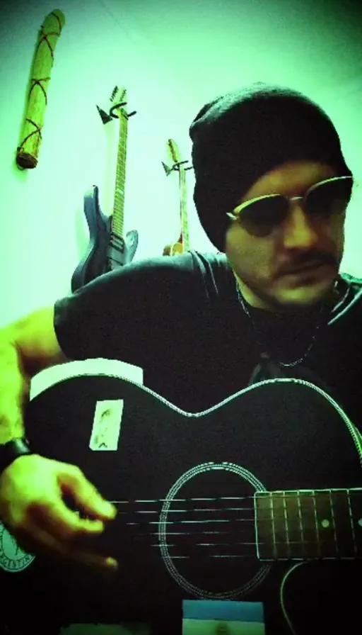 a man wearing sunglasses and a beanie playing a guitar