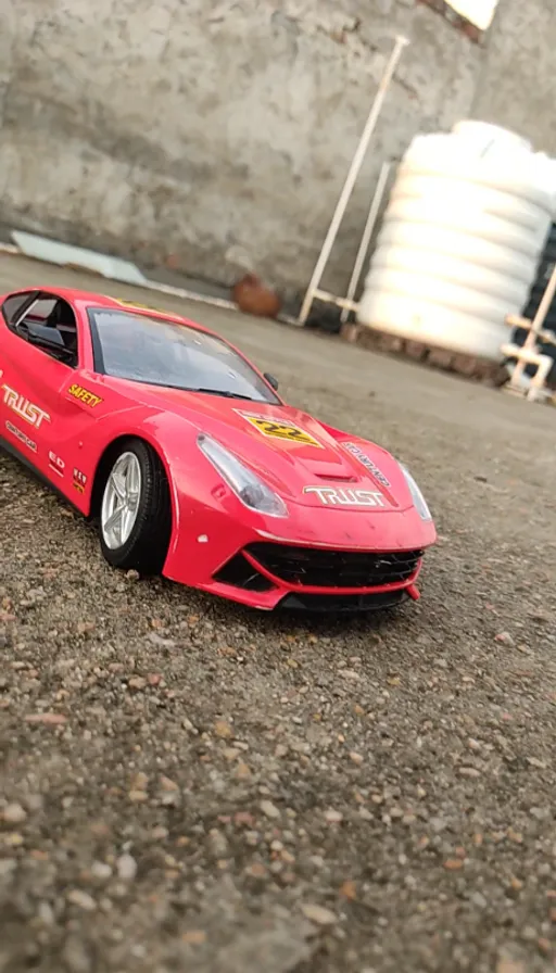 a red toy car sitting on top of a gravel road