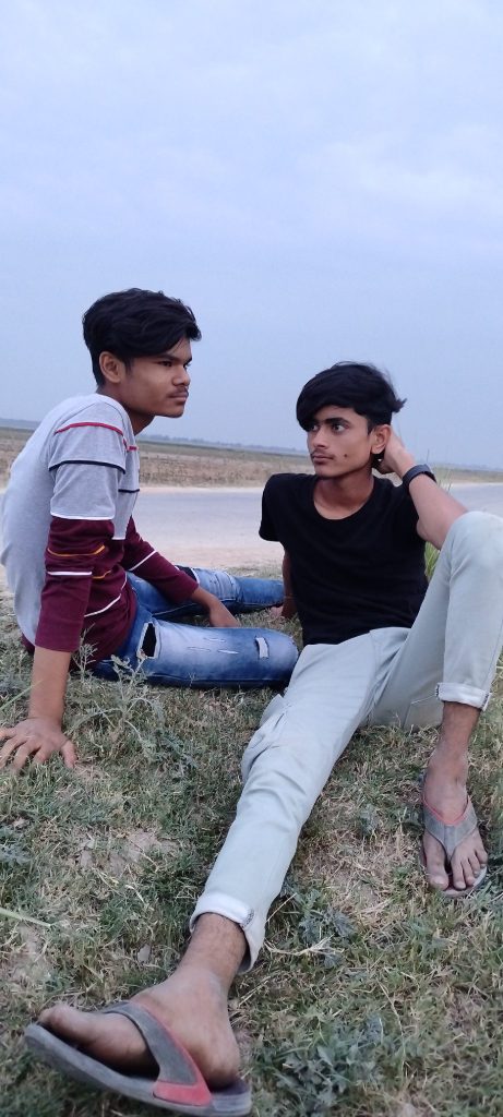 a couple of men sitting on top of a grass covered field