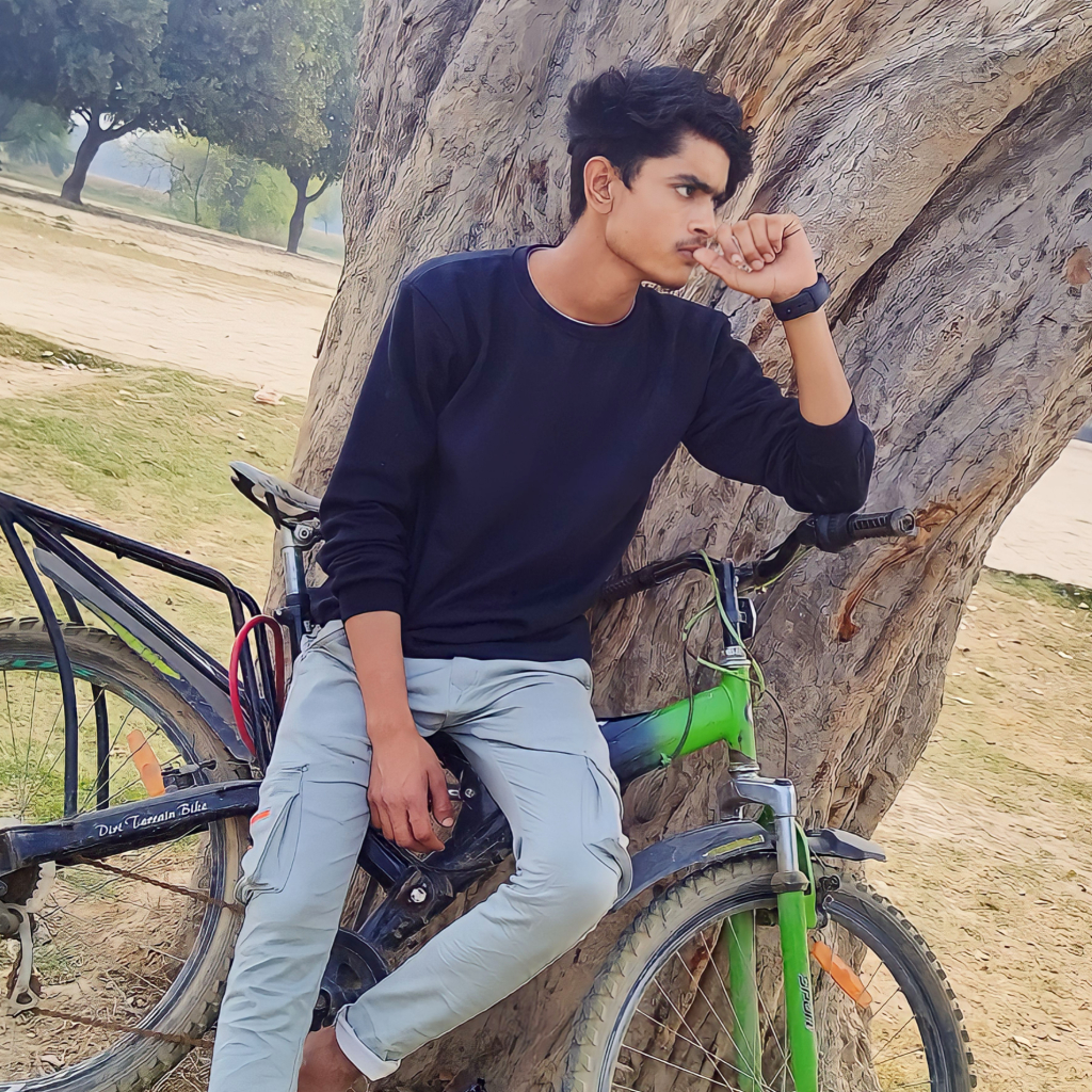 a young man sitting on top of a bike next to a tree