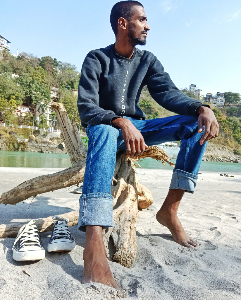 a man sitting on a tree stump on a beach