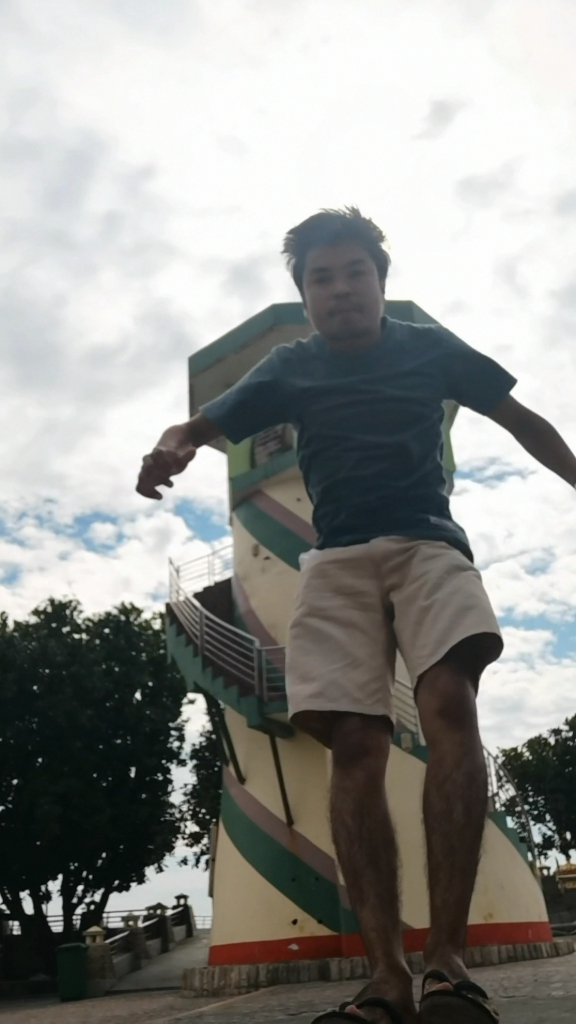 a man riding a skateboard down a sidewalk. on a bright day, with a bright blue sky in the background