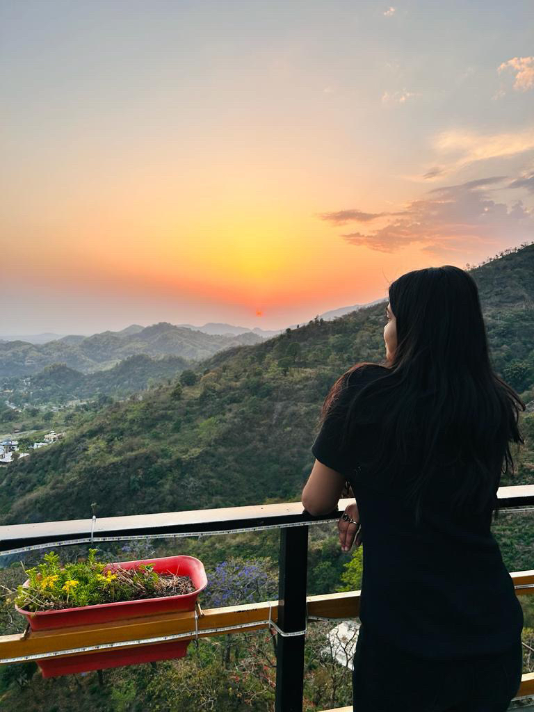 a woman standing on a balcony watching the sunset