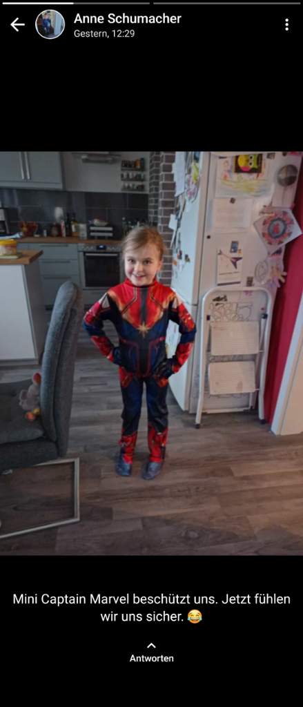 a little boy in a spiderman costume standing in a kitchen