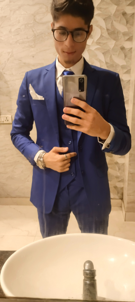 A man in a red suit taking a selfie. replace the blue suit with a red suit and man with a green suit