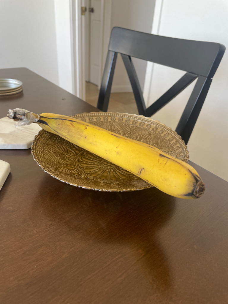 a banana sitting on top of a wooden table. replace the banana with a Donald Trump figure