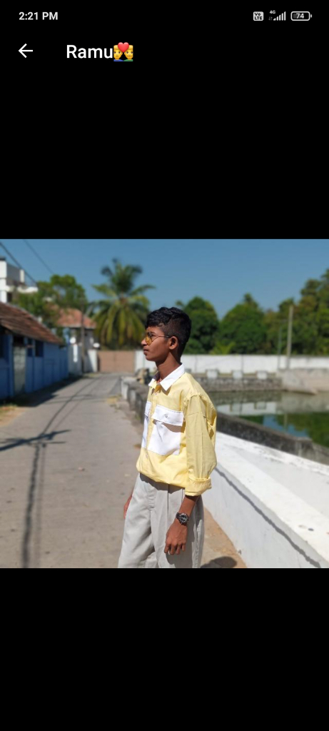 a young boy standing on a sidewalk next to a body of water