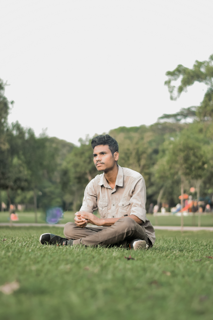 a man sitting on the grass in a park