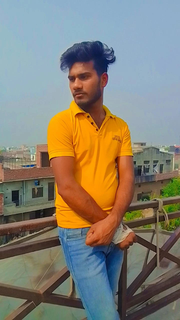 a man in a yellow shirt sitting on a railing