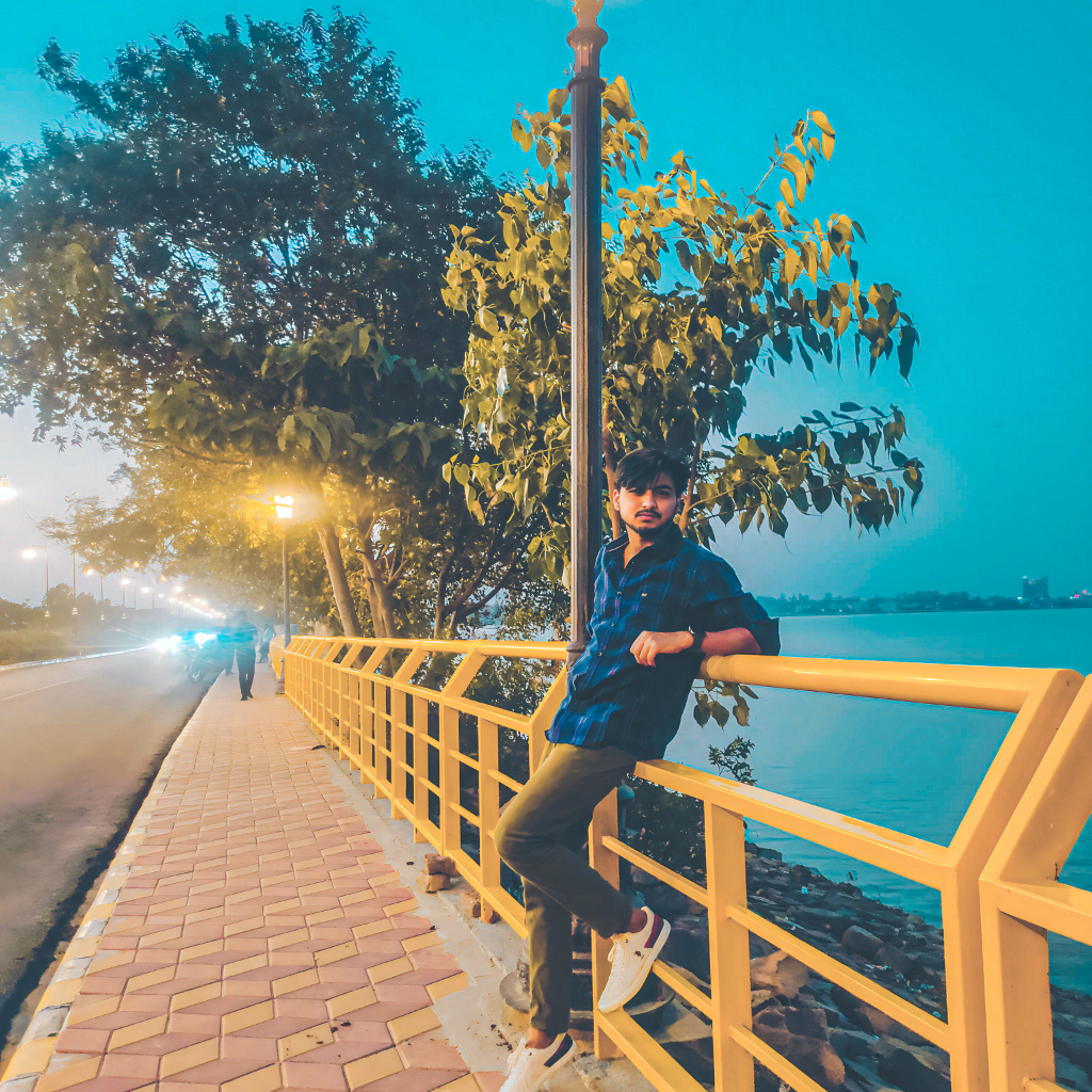 a man leaning on a yellow railing next to a tree