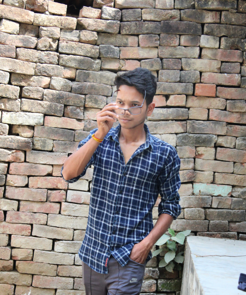 a man standing in front of a brick wall talking on a cell phone