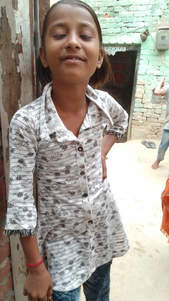 a young girl standing next to a brick wall