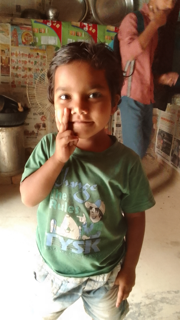 A little boy stands in a kitchen with no woman in the background. Woman in the background removed.