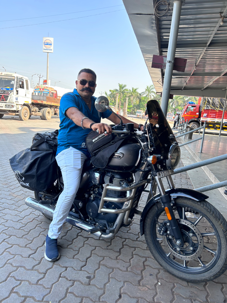 A man sitting on a motorcycle at a gas station. Now he's the super man. Man chenge the super man