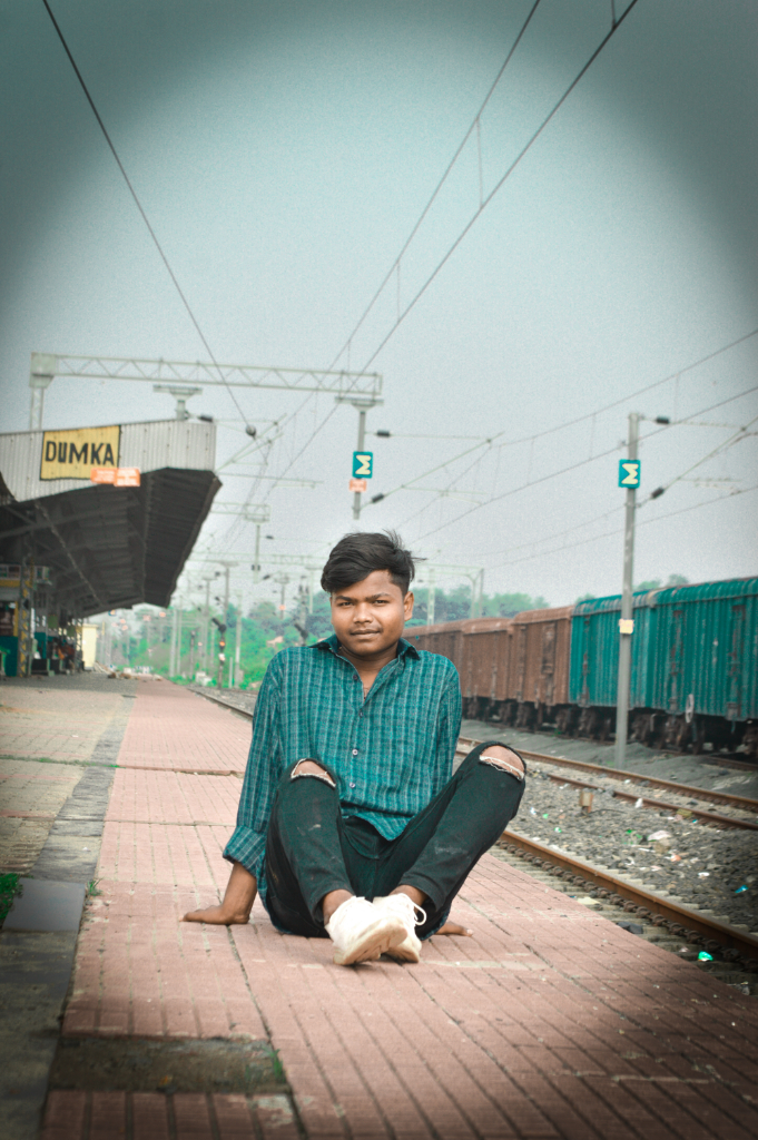 a man sitting on the ground next to a train track