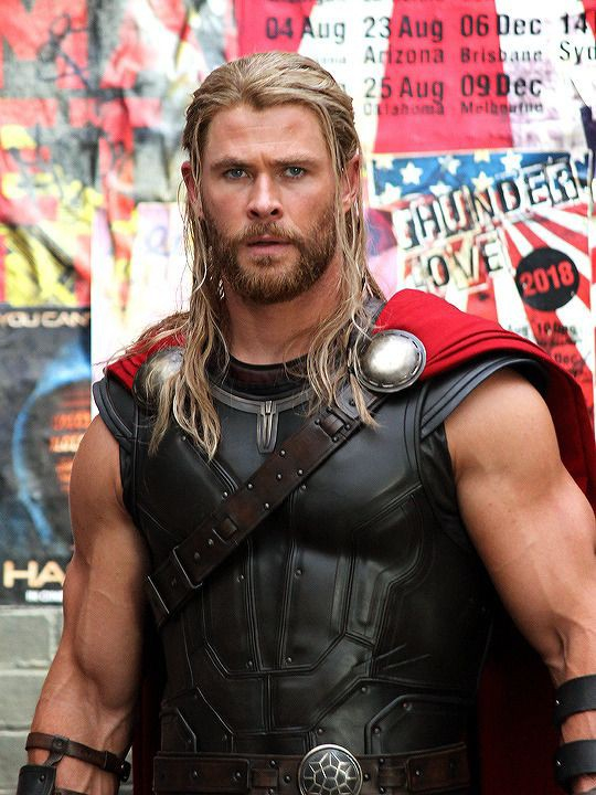 a man dressed as thor is standing in front of a wall