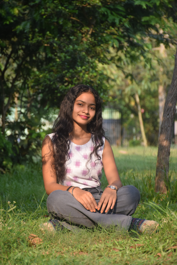 a woman sitting on the ground in the grass