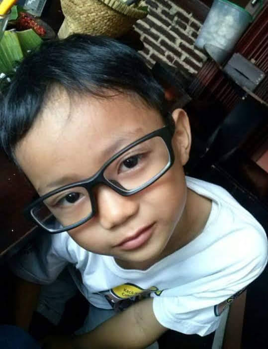 a young boy wearing glasses and a white shirt