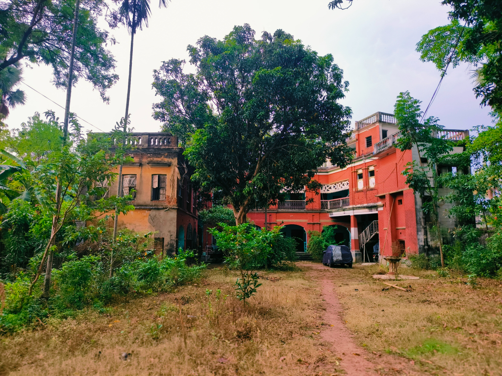 A red building in the middle of a cool green forest. Add a cool green tree behind the building.