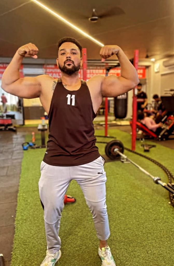 a man in a gym with his arms up