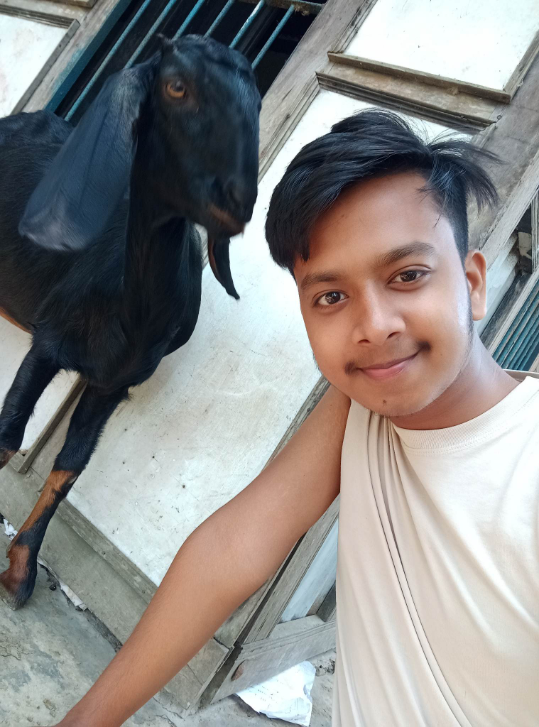 a young man standing next to a black goat