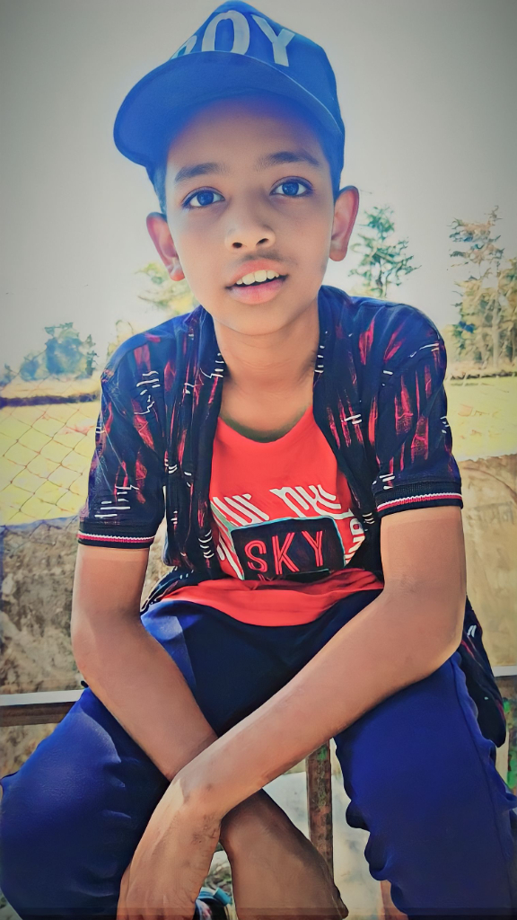 a young boy sitting on a bench wearing a red hat. change blue hat to red