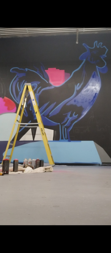 a man standing on a ladder in front of a large mural