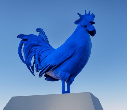 a statue of a blue rooster on top of a building