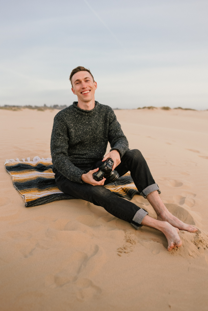 a man sitting in the sand with a camera