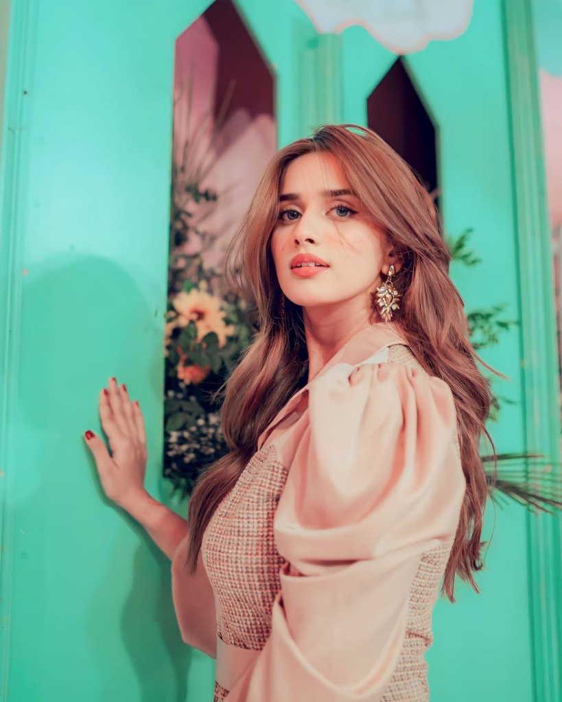 a woman standing in front of a green wall