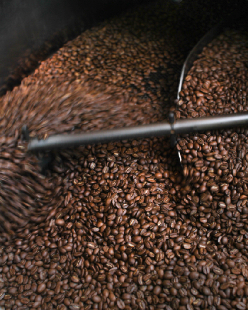 a bunch of little people stirring coffee beans representing different countries. Add little people stirring the beans with long poles. The beans could be representing different countries.