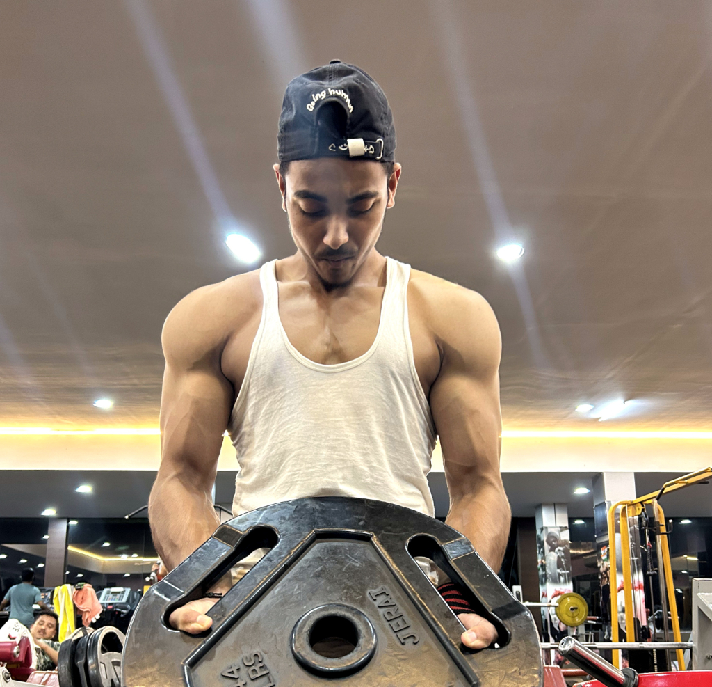 a man holding a large metal object in a gym